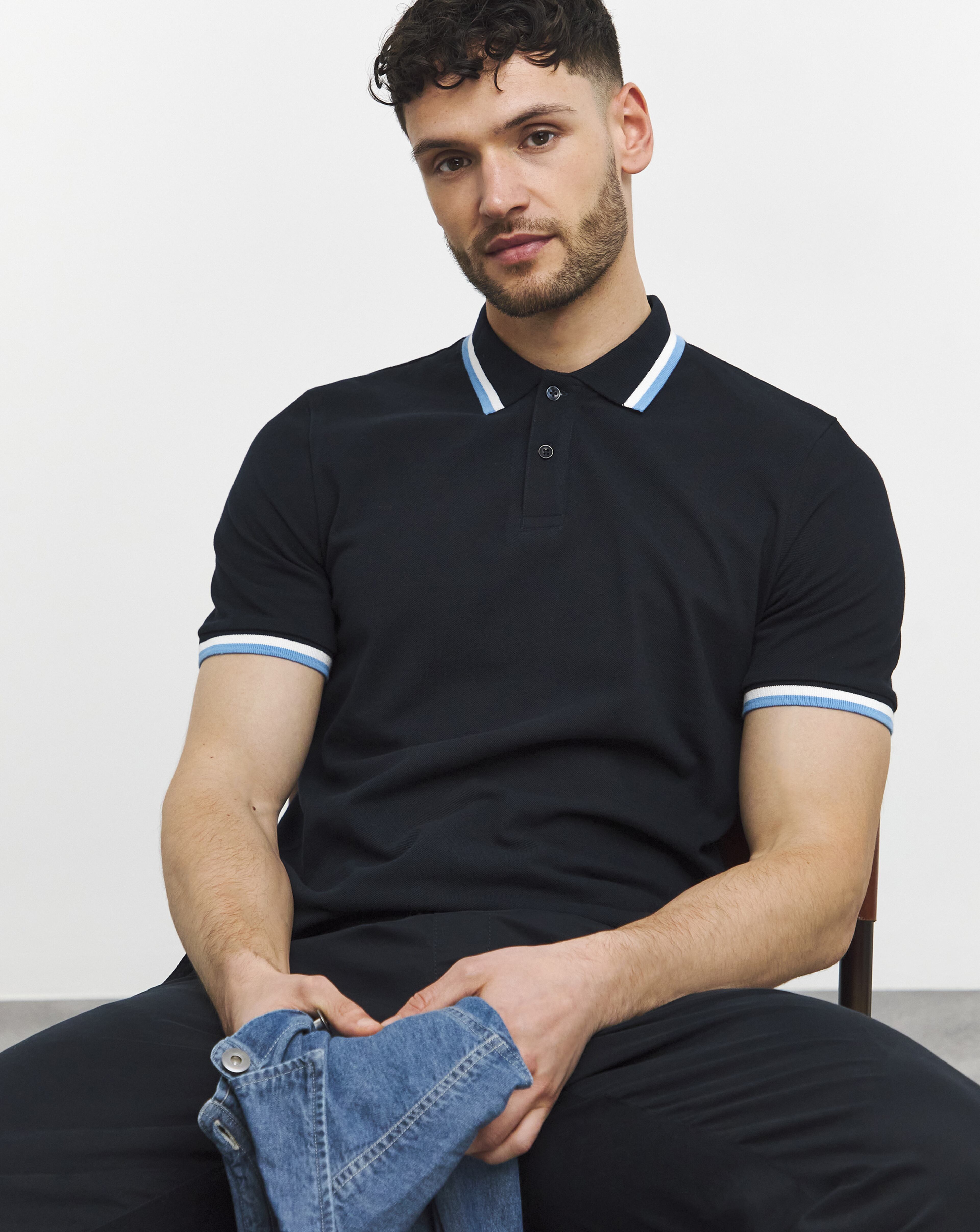 Man sat wearing a navy blue polo shirt